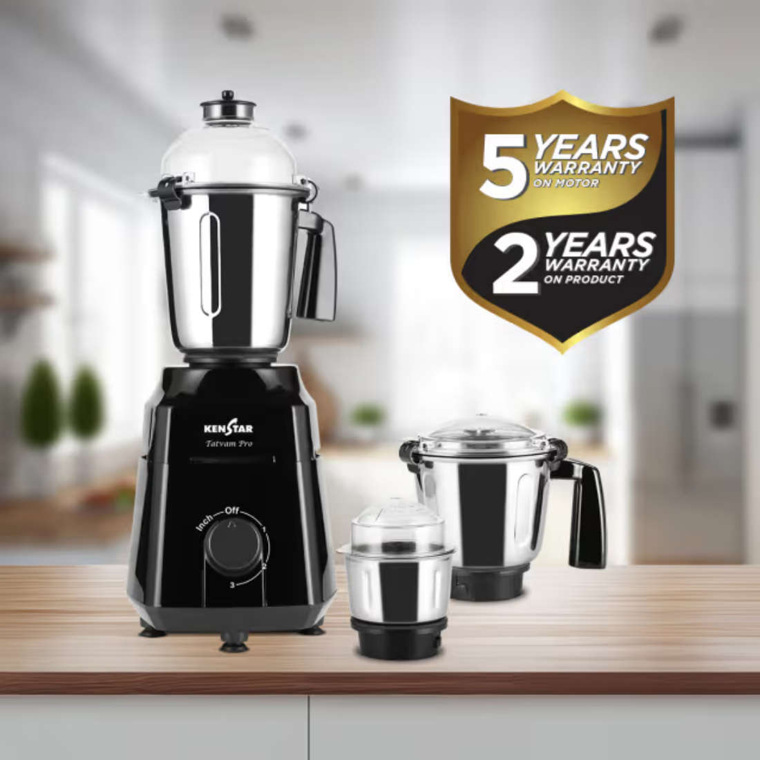 Kenstar Sahyan Pro electric blender shown with its three jars on a wooden countertop, with a blurred kitchen background and a gold and black warranty badge overlay on the right.