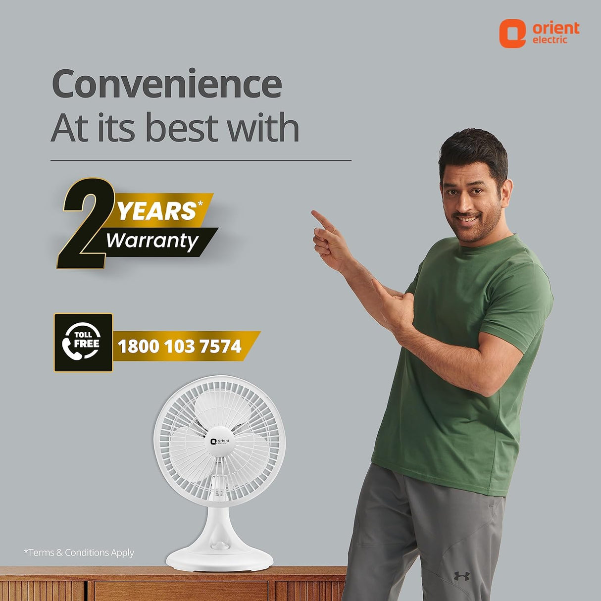 Man pointing to a white fan with 'Orient Electric' branding and warranty information on a gray background.