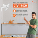 Person in a kitchen pointing at a ceiling fan with 'Orient Electric' branding and CT Tech features.