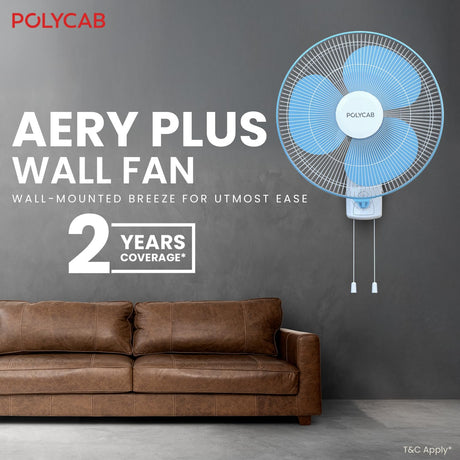 Wall-mounted fan with POLYCARB branding in a room with a brown sofa.