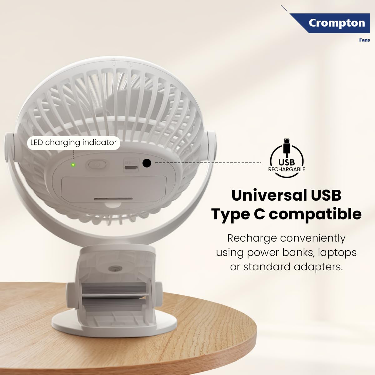 White portable fan with USB charging indicator on a wooden surface, featuring Crompton logo.