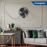 Crompton wall fan mounted on a wall in a living room setting with a sofa and decor.