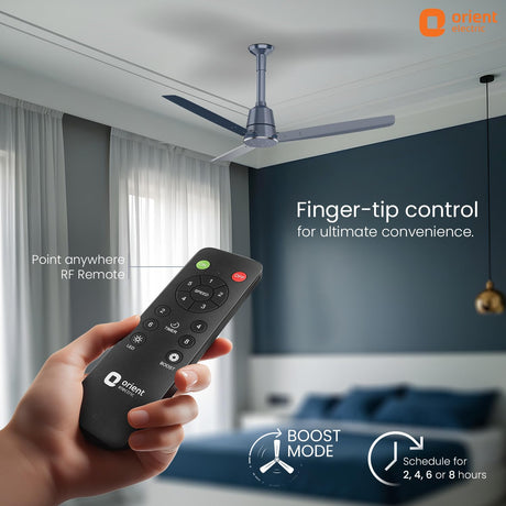 Hand holding a remote control with a ceiling fan in the background, featuring Orient Electric branding.