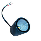A black cylindrical LED light fixture with a textured silver reflector and a single wire with red, green, and black strands, placed on a wooden table.