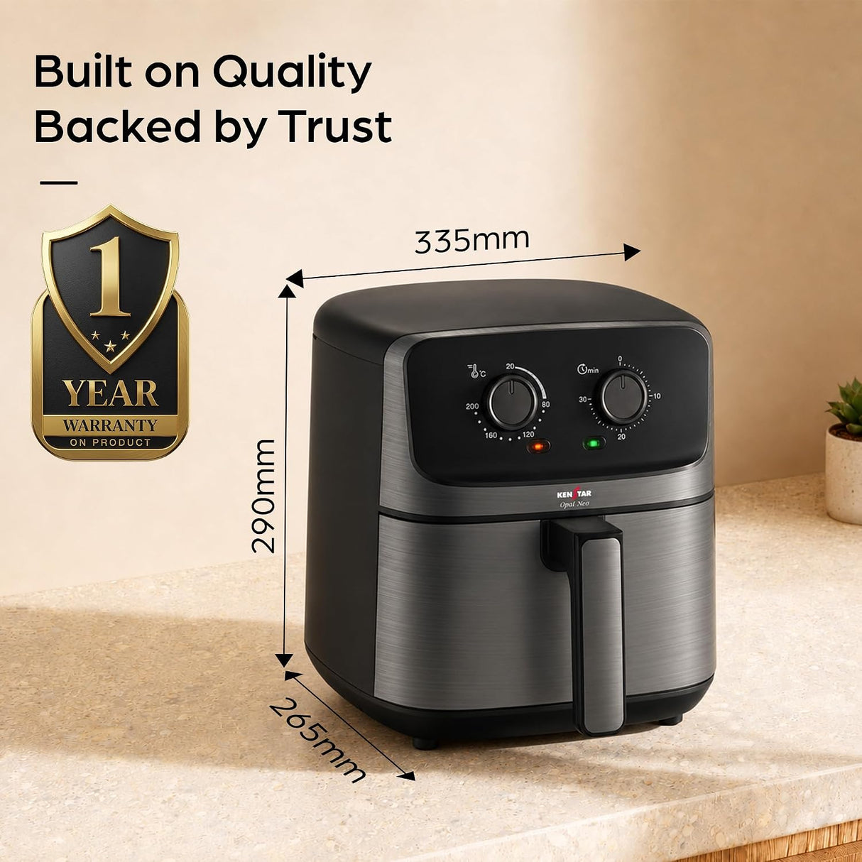 A black and stainless steel air fryer sits on a beige countertop in a kitchen-like setting, with overlaid dimension arrows showing 335mm width, 290mm height, and 265mm depth. Text at the top reads 'Built on Quality Backed by Trust,' and a gold '1 Year Warranty' badge appears on the left.