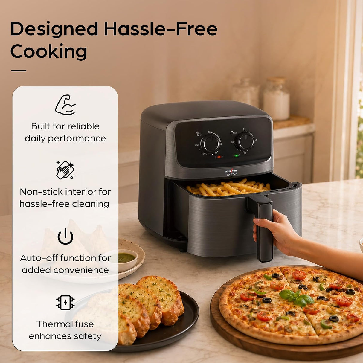A countertop air fryer in a warm kitchen setting, shown with a hand pulling the basket out. A plate of garlic bread and a pizza sit nearby, and large marketing text on the left reads 'Designed Hassle-Free Cooking' with feature callouts.