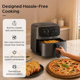 A countertop air fryer in a warm kitchen setting, shown with a hand pulling the basket out. A plate of garlic bread and a pizza sit nearby, and large marketing text on the left reads 'Designed Hassle-Free Cooking' with feature callouts.