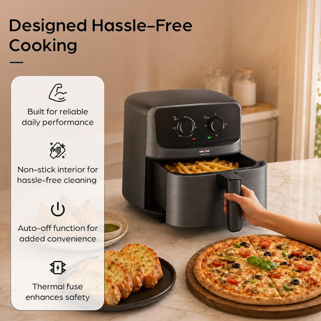 A countertop air fryer in a warm kitchen setting, shown with a hand pulling the basket out. A plate of garlic bread and a pizza sit nearby, and large marketing text on the left reads 'Designed Hassle-Free Cooking' with feature callouts.