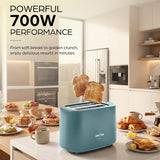 A light blue 4-slice toaster sits on a kitchen counter with two slices of toast popping out. The scene is set in a bright, modern kitchen with breakfast items on the counter, and promotional text in the upper left reads 'POWERFUL 700W PERFORMANCE'.