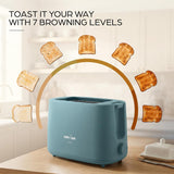 A blue Kenstar toaster sits on a wooden table in a bright kitchen setting, with floating slices of toast arranged in a semi-circle and the text 'TOAST IT YOUR WAY WITH 7 BROWNING LEVELS' above it.