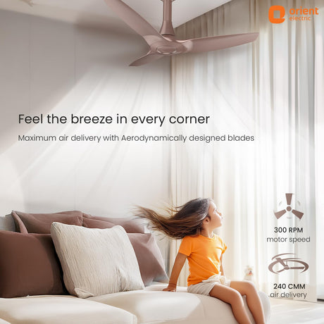 Ceiling fan in a room with a child sitting on a couch, featuring Orient Electric branding.