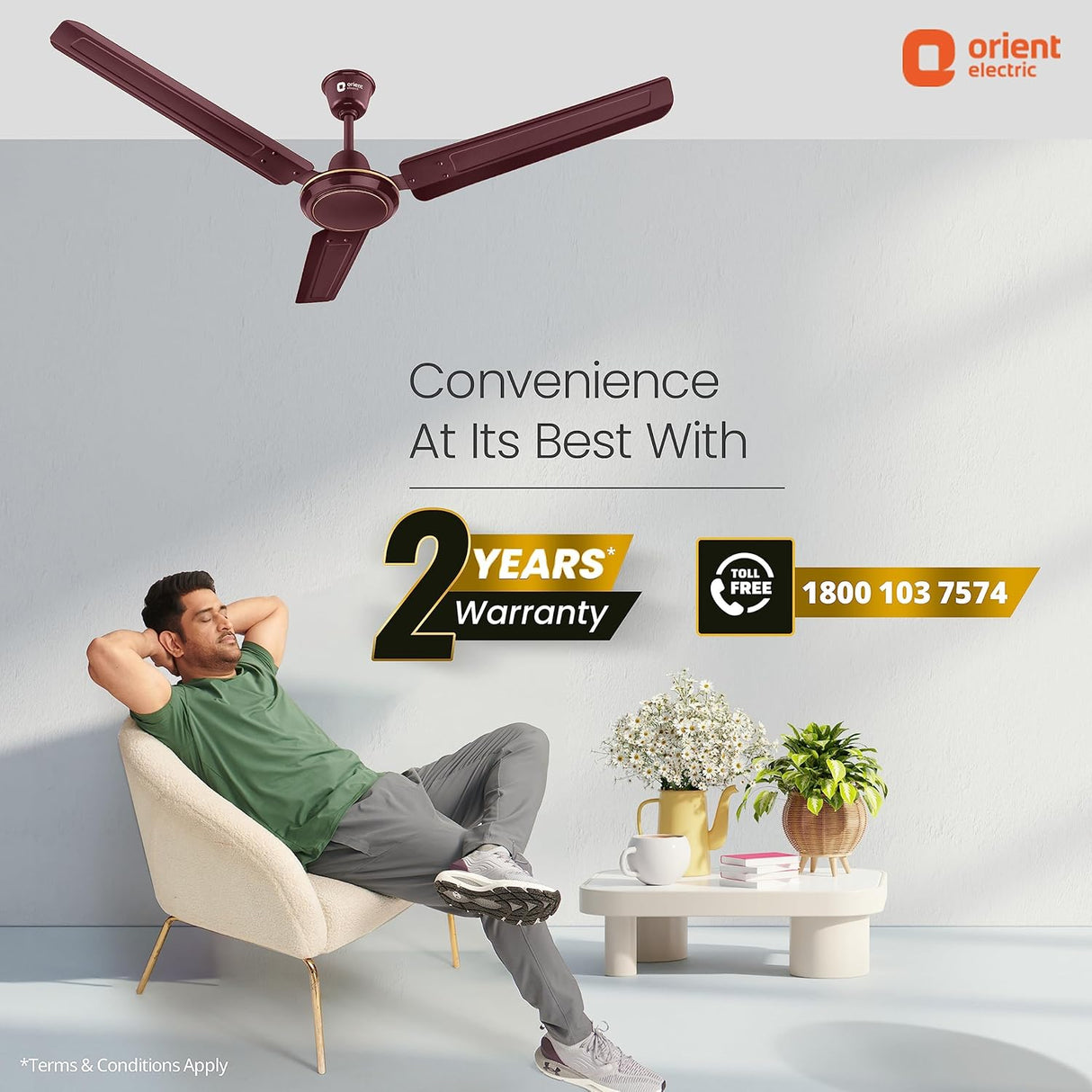 Man relaxing in a chair with a ceiling fan above, featuring Orient Electric branding.
