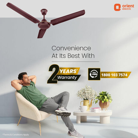 Man relaxing in a chair with a ceiling fan above, featuring Orient Electric branding.