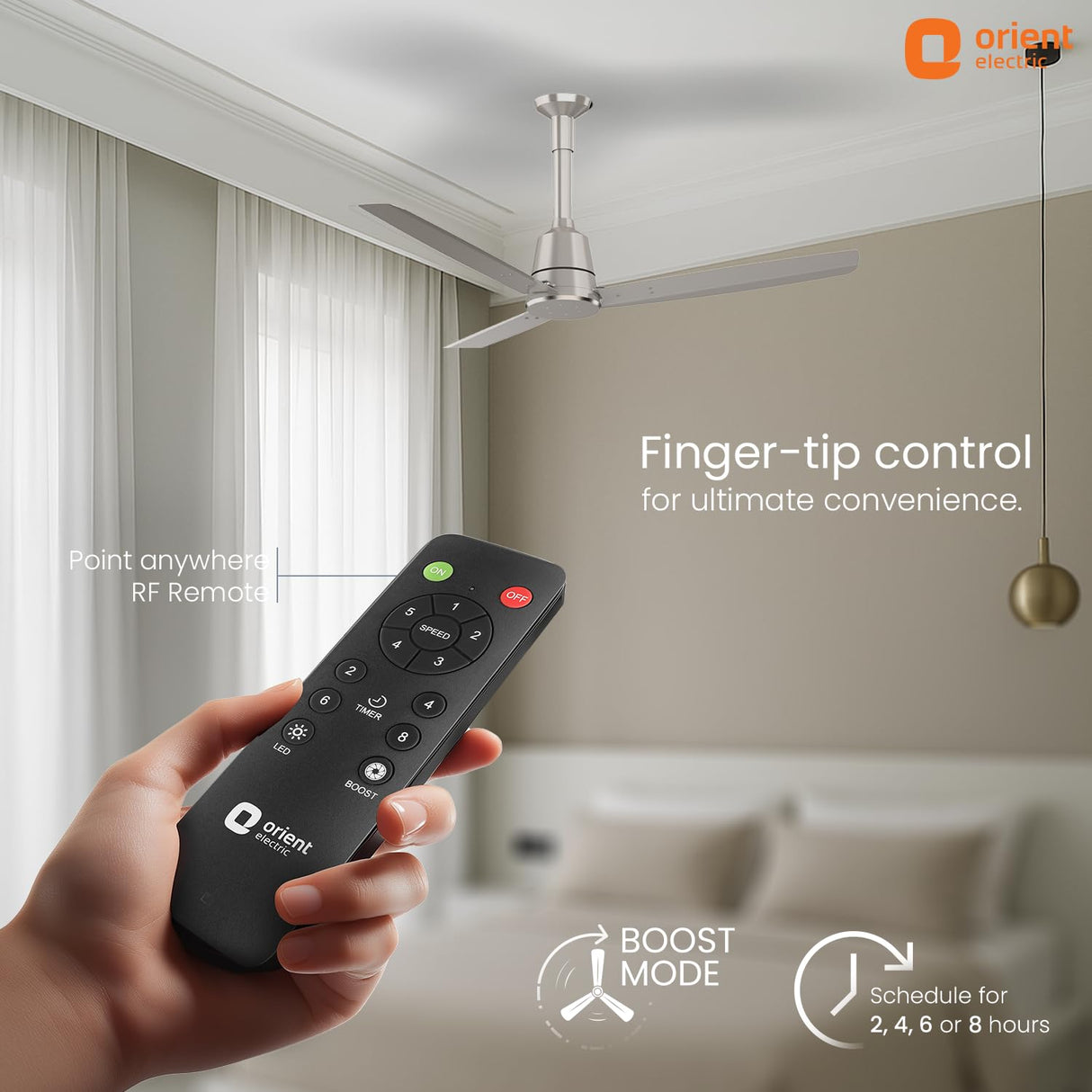 Hand holding a remote control with an orient electric ceiling fan in the background