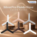 Crompton SilentPro Fluido Wave color range display featuring five Y-shaped desk fans in different finishes: Snow White, Cinnamon Blush, Fog Grey, Matt Black, Sheesham Wood, and Conch Cream, arranged on brown display pedestals against a warm beige background.