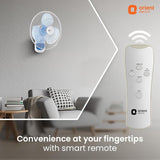 Wall-mounted fan and remote control with Orient Electric branding in a living room setting.
