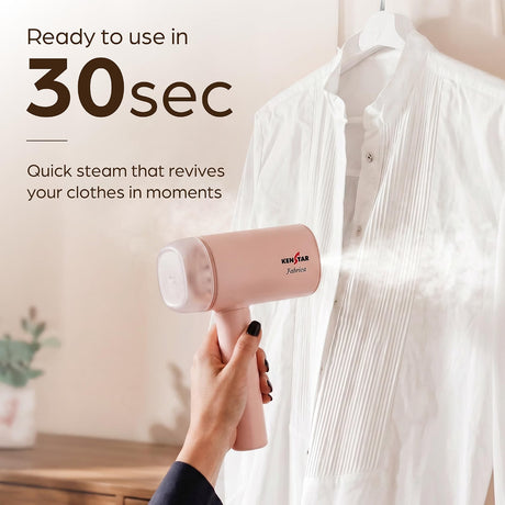 A pink handheld garment steamer is being used by a hand to steam a white pleated button-up shirt. The image includes marketing text that reads 'Ready to use in 30sec Quick steam that revives your clothes in moments' and shows the brand name 'KENSTAR' on the steamer.