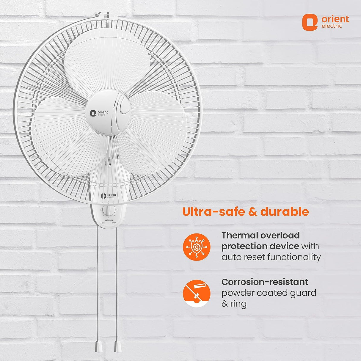Wall-mounted fan with safety features on a white brick wall background, featuring the Orient Electric logo.